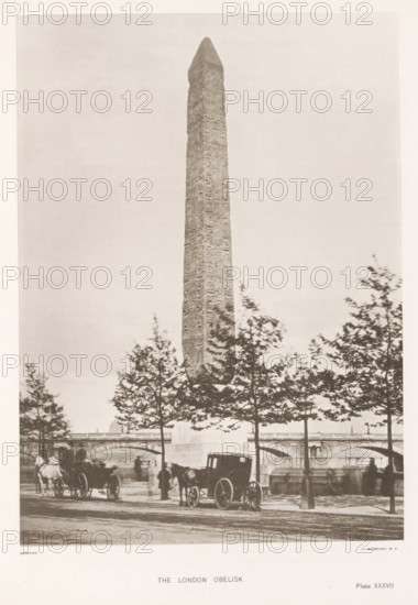 The London obelisk, page, photomechanical print, number: 'Plate XXXVII', cliché maker: Harroun & Bierstadt (possibly), New York (city), c. 1881, photographer, printer (person), North America, paper, collotype, artotype, height 266 mm x width 192 mm, obelisk, needle, London, Cleopatra's needle (London), A tall stone obelisk with carved surface rises vertically from a base and dominates the scene, framed by a row of trees with leafy branches in the foreground; below the obelisk a bridge with arches spans the background and there are horse-drawn carriages and figures on a paved street near the curb, with a silhouette of a cityscape visible behind the bridge.