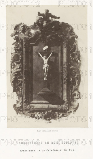 Crucifix in wooden frame from the cathedral of Le Puy-en-Velay, Encadrement en bois sculpté, photograph, page, inscription: 'appartenant a la Cathédrale du Puy.', number: 'PL. 24.', photographer: Hippolyte Malègue, France, c. 1850 - in or before 1857, paper, salted paper print, height 188 mm x width 125 mm, God the Father represented as human being, usually with crown or tiara or scepter and, or globe, the crucifixion of Christ: Christ's death on the cross, Golgotha (Matthew 27:45-58, Mark 15:33-45, Luke 23:44-52, John 19:25-38), sculpture (relief, sculpture), A framed ornate relief occupies the center of the image, showing a sculpted figure on a cross suspended within a deep rectangular panel; the frame is richly carved with swirling acanthus-like foliage, shells, and clustered decorative elements, and a cherubic or bearded figure sits atop the frame with arms extended; the relief interior is darker than the surrounding carved border, and a shadow falls from the lower part of the cros...