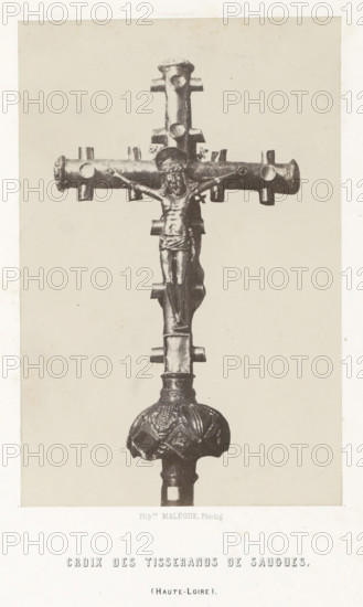 Cross of the weavers, from Saugues, Croix des tisserands de Saugues, photograph, page, number: 'PL. 5.', inscription: '(Haute-Loire).', photographer: Hippolyte Malègue, France, c. 1850 - in or before 1857, paper, salted paper print, height 202 mm x width 133 mm, crucifix, personal devotion, A vertical photograph of a metal crucifix mounted on a decorative stem, shown against a plain light background. The crucifix features a horizontal crossbar with rounded ends and small protruding cylindrical nodes, and a vertical shaft with matching nodes. A sculpted figure with a halo is affixed to the cross, depicted with outstretched arms, a draped lower garment, and visible facial and torso details. Below the cross, the stem widens into an ornamented rounded knob with embossed patterns and a textured surface, and the lower shaft continues downward out of frame. The image has a narrow light border around it.