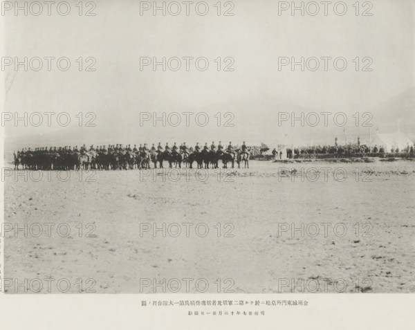 A service hero in memory of those fallen in the second army, at the cemetery outside the east gate of Kinchow: the salute of the first cavalry battalion, page, photomechanical print, inscription: 'The fall of Kinchow.', photographer: Ordnance Survey, China, cliché maker: Kazumasa Ogawa, Japan, 1894-11-21, paper, collotype, photoprint, height 203 mm x width 284 mm, horse, funerary ceremonial, military salutes, A wide, pale landscape fills the image with a low horizon line, and near that horizon a long line of mounted figures forms a dark silhouette across the scene, each person seated on a horse and wearing a uniform with high headgear; to the right of the mounted line there are a few tents and groups of standing people gathered around them, with some upright poles or standards nearby, while the foreground shows a flat, textured ground with scattered small clumps and rough patches.