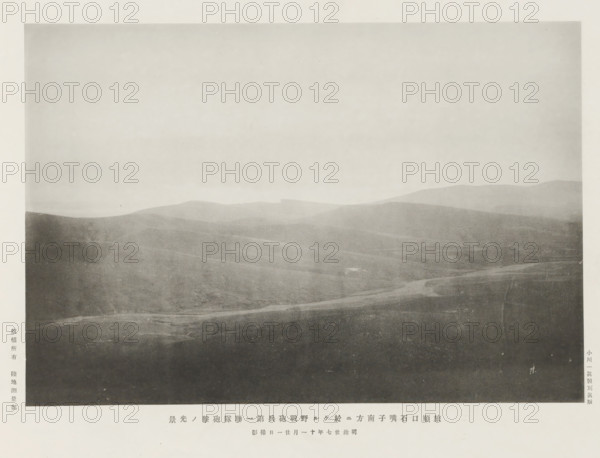 Attack of the first artillery regiment, S. of Shihtsuytse, at Port Arthur, page, photomechanical print, inscription: 'The fall of Port Arthur.', photographer: Ordnance Survey, Manchuria, cliché maker: Kazumasa Ogawa, Japan, 1894-11-21, paper, collotype, photoprint, height 190 mm x width 278 mm, army 'en route', A grayscale photograph showing a wide, gently rolling landscape with layered hills fading into the distance under a pale sky, the foreground appearing darker with subtle textures and a faint winding path or depression, midground hills with soft gradients of shadow and light, and distant ridgelines that are lighter and more diffused.