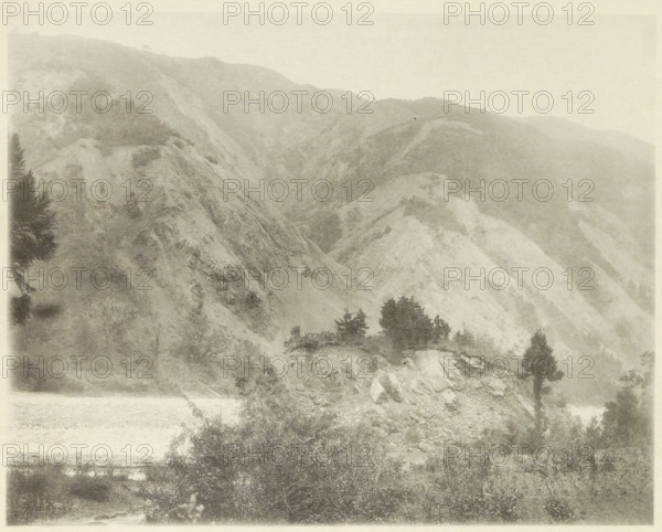 Landslides in the Neo Valley in Japan after an earthquake, page, photomechanical print, Japan, cliché maker: Kazumasa Ogawa, after 1891-10-28 - in or before 1892, photographer, paper, collotype, photoprint, height 227 mm x width 288 mm, landslide, consequences of an earthquake, Mino–Owari earthquake 1891, A wide, monochrome landscape showing steep, rocky hills and ridges with sparse vegetation, several clusters of dark trees on a lighter rocky outcrop, dense bushes and shrubs in the foreground, and layered slopes fading into the misty background.