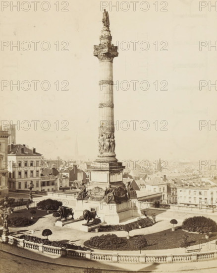 View of the Congress Column in Brussels, Bruxelles - Place et Colonne du Congrès, photograph, page, name: '(Phot. de Brand frères, rue de la Madeleine, 32.)', photographer: Brand Frères, Brussels, c. 1862 - c. 1872, paper, albumen print, albumendruk, height 187 mm x width 149 mm, Photo on page 7., monument, statue, square, circus, column, pillar, architecture, Congress Column, A tall decorative column rises from a large stone pedestal surrounded by sculpted figures and reclining statues, with ornate carvings and wreath-like bands along the column shaft and a standing statue at the top; two large lion sculptures sit on stepped platforms at the base, flanked by trimmed round shrubs and landscaped garden beds with low hedges and small potted trees; a balustraded terrace encloses the foreground and a wide paved roadway runs below it; surrounding buildings with multi-story facades, pitched roofs, and rows of windows fill the midground and background, where a distant cityscape of rooftops an...