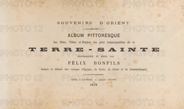 Souvenirs d'orient : album pittoresque des sites, villes et ruines les plus remarquables de la Terre-Sainte, book, annotation: 'NOV, 2002', photographer: Félix Bonfils, writer (clerical worker): Félix Bonfils, publisher: Félix Bonfils, Alès, 1878, Félix Bonfils, photographer, writer (clerical worker), publisher, paper, printing, albumen print, albumendruk, height 178 mm x width 294 mm x thickness 45 mm, A faded, aged page with a central arrangement of dark printed lines and larger bold words; the paper shows brownish foxing spots and uneven discoloration across a light beige background, with a thin horizontal decorative rule above the central block and several lines of typographic elements in varying sizes and weights, including a prominent wide word set with spaced letters, smaller serif lines above and below, and a narrow decorative divider; small printed lines appear near the bottom and the overall surface has subtle stains and slight edge darkening.