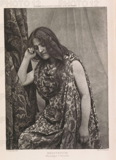 Méditation, Portrait of an unknown woman, page, photomechanical print, photographer: C. Vieuille, cliché maker: Dujardin, printer (person): Charles Wittmann, c. 1886 - in or before 1896, printer (person), paper, photoaquatint, height 170 mm x width 121 mm, adult woman, curtains, dress, gown, A black-and-white photograph of a seated young woman with long wavy hair wearing a patterned draped garment, her head tilted slightly downward and resting against one hand, the other arm hanging relaxed at her side, with patterned fabric visible behind and around her and a plain backdrop behind her.