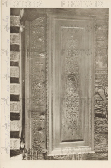 Virginal Duke of Cleves from the collection of Antonin Terme, page, photomechanical print, annotation: 'Virginale - ... en noyer sculpté en 1568 - aux poor du cleves Julius et Burgh, ... collection A. Terme, 129 =', c. 1880 - in or before 1885, paper, collotype, photoprint, height 137 mm x width 215 mm, Print is loose in the book., spinet, virginal, art collection, art gallery, A grayscale photograph showing a close-up of an ornate carved wooden panel and adjacent decorative elements, with intricate floral and scrollwork reliefs, oval medallion designs, and framed rectangular borders, plus a carved frieze featuring stylized motifs and small circular portraits, and a row of textured book spines with raised bands and patterned covers along one edge.