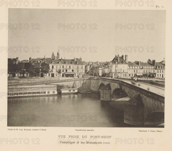 View of the Pont Neuf in Compiègne, France, Vue Prize du Pont-Neuf, Compiègne et ses Monuments (oise), page, photomechanical print, number: 'Pl. I.', inscription: 'Reproduction interdite.', maker: Jules Royer, Compiègne, maker: Augustin Boutique, Douai, c. 1890 - in or before 1895, paper, collotype, photoprint, height 121 mm x width 160 mm, Print opposite title page., city-view in general, 'veduta', bridge, A sepia-toned photograph showing a river with a stone arched bridge crossing it, a riverside building with windows and a long covered structure floating at the waterline, and a row of multi-story buildings with pitched roofs, chimneys, and storefronts lining the far bank; there are small groups of people on the bridge and along the street, trees in front of some buildings, and architectural details like a tower and spires visible above the rooftops.