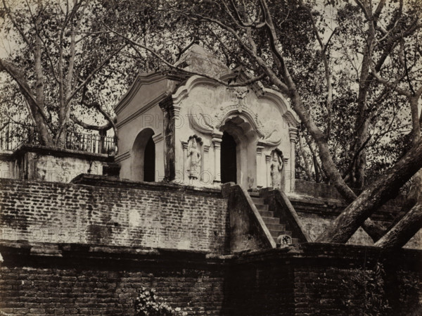 Second Flight of Steps Leading to the Sacred Bo Tree., Steps leading to the sacred bodhi tree in Anuradhapura, album page, photograph, Part of Album with 50 photos of a trip through Southeast Asia., photographer: Charles T. Scowen & Co., Anuradhapura, c. 1875 - c. 1880, South Asia, paper, albumen print, height 218 mm x width 279 mm, temple, shrine, Hinduism, Buddhism, Jainism, An ornate stone structure with a curved, decorative facade sits atop a weathered brick platform, accessed by a narrow flight of stone steps; the facade features sculpted niches containing standing figures and arched openings, flanked by pilasters and ornamental scrollwork, while trees with spreading branches and dense foliage surround and partially frame the building, and a metal railing runs along a raised area behind the structure.