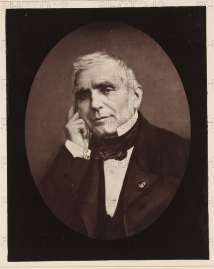 Portrait of Eugène Scribe, Eugene Scribe. Ne a Paris, le 25 decembre, decede le 20 fevrier 1861, page, photomechanical print, inscription: '126, boul. Magenta.-Paris.', photographer: Félix Nadar, cliché maker: Goupil & Cie., c. 1850 - in or before 1861, paper, Woodburytype, Woodburytypepie, height 228 mm x width 182 mm, Person, Eugène Scribe, portrait of a writer, An oval-framed sepia portrait of an older man shown from the chest up, with light-colored hair and sideburns, wearing a dark suit jacket, waistcoat, white shirt, and a dark cravat; he rests his head on his hand with fingers touching his cheek, looking slightly forward with a neutral expression, and a small decorative pin is visible on his jacket lapel.