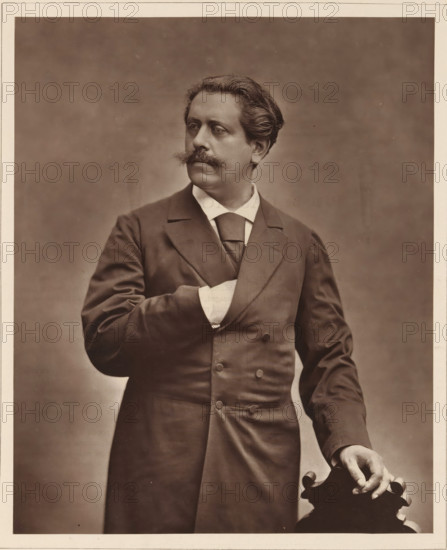 Paul de Cassagnac. Ne le 2 decembre 1842, a La Guadeloupe, Portrait of Paul de Cassagnac, page, photomechanical print, inscription: '126, boul. Magenta.-Paris.', photographer: Charles Louis Klary, cliché maker: Goupil & Cie., c. 1876 - in or before 1879, paper, Woodburytype, Woodburytypepie, height 228 mm x width 185 mm, Person, Paul de Cassagnac, journalist, reporter, A sepia-toned portrait of a man shown from the thighs up wearing a dark double-breasted coat with wide lapels and a light-colored shirt and tie, his left hand tucked inside his coat and his right hand resting on the carved top of a wooden chair; he has wavy hair swept back, a prominent mustache, and is looking slightly to his left against a plain, softly textured background.