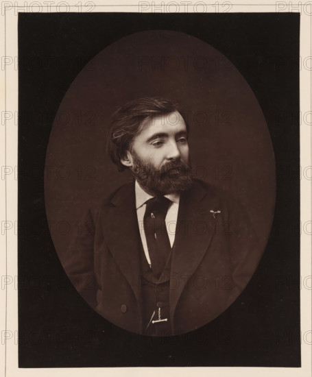 De Bornier. Ne a Lunel, en 1825, Portrait of Henri de Bornier, page, photomechanical print, inscription: '126, boul. Magenta.-Paris.', photographer: Ferdinand Mulnier, cliché maker: Goupil & Cie., c. 1876 - in or before 1879, paper, Woodburytype, Woodburytypepie, height 229 mm x width 182 mm, Person, Henri de Bornier, writer, poet, author, A sepia-toned oval portrait of a man from the chest up, showing a head with dark, combed hair and a full beard and mustache, a contemplative gaze directed slightly to the side, wearing a dark suit jacket over a waistcoat and a white shirt with a dark tie, a small pin or flower on the jacket lapel, and a watch chain visible at the waist, set against a darker rectangular background with a light border.
