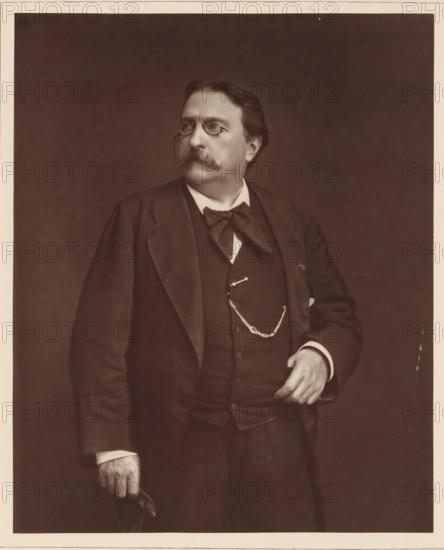 H. Giacomelli. Ne a Paris, le 1er avril 1822, Portrait of Hector Giacomelli, page, photomechanical print, inscription: '126, boul. Magenta.-Paris.', photographer: Ferdinand Mulnier, cliché maker: Goupil & Cie., c. 1876 - in or before 1879, paper, Woodburytype, Woodburytypepie, height 229 mm x width 185 mm, Person, Hector Giacomelli, painting, drawing and the graphic arts, A sepia-toned portrait of a middle-aged man shown from the hips up wearing a dark three-piece suit, a large bow tie, and a pocket watch chain across his vest; he has a full mustache and short, combed hair, and he is wearing pince-nez glasses with a chain; his left hand rests near his waist while his right hand holds a folded hat, and he is looking slightly to his left against a plain dark background.