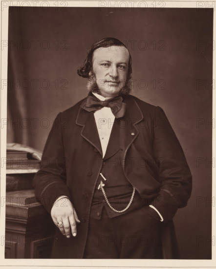 A. Tardieu. Ne a Paris, le 10 mars 1818, mort le 12 janvier 1879, Portrait of Auguste Ambroise Tardieu, page, photomechanical print, inscription: '126, boul. Magenta.-Paris.', cliché maker: Goupil & Cie., c. 1876 - in or before 1879, photographer, paper, Woodburytype, Woodburytypie, height 228 mm x width 187 mm, Person, Auguste Ambroise Tardieu, physician, doctor, A sepia portrait of a seated man shown from the waist up wearing a dark suit jacket with a light-colored shirt and a large bow tie, with visible sideburns and neatly combed hair, one hand resting on a wooden surface beside stacked books and the other hand tucked into a pocket, a chain draped from his waistcoat and a ring on one finger, plain backdrop behind him.