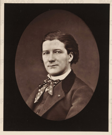 Victorien Sardou. Ne a Paris, le 7 septembre 1831, Portrait of Victorien Sardou, page, photomechanical print, inscription: '126, boul. Magenta.-Paris.', photographer: Ferdinand Mulnier, cliché maker: Goupil & Cie., c. 1876 - in or before 1879, paper, Woodburytype, Woodburytypepie, height 226 mm x width 185 mm, Person, Victorien Sardou, portrait of a writer, A sepia portrait of a person shown from the chest up inside an oval vignette, with dark background surrounding the oval; the person has neatly combed dark hair, a smooth complexion, and a calm facial expression with eyes looking slightly to the side, wearing a high collared shirt, a patterned neckerchief tied in a loose knot, and a dark tailored jacket with a lapel and visible buttons.