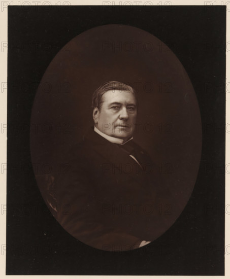 Portrait of Eugène Labiche, Eugène Labiche. Ne a Paris, le 6 mai 1815, page, photomechanical print, inscription: '126, boul. Magenta.-Paris.', photographer: Ferdinand Mulnier, cliché maker: Goupil & Cie., c. 1876 - in or before 1879, paper, Woodburytype, Woodburytypepie, height 228 mm x width 184 mm, Person, Eugène Labiche, portrait of a writer, A sepia-toned oval portrait of a middle-aged man shown from the chest up against a dark rectangular background, with neatly combed hair, a high collar, and a dark suit; he faces slightly to his left with a neutral expression, and the oval vignette softens the edges of his shoulders and torso.
