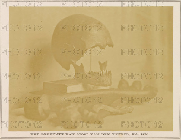 Bones of Joost van den Vondel, The Bones of Joost van den Vondel, Feb. 1870, photograph, page, photographer: P. Oosterhuis, 1870-02, paper, albumen print, height 125 mm x width 165 mm, (human) skull, (human) skeleton, A sepia-toned photograph shows a human skull displayed in profile with the cranium elevated above the jaw, which is positioned slightly forward and rests near a rectangular book-like object; the skull and jaw appear aged and fragmented with missing sections and rough edges, and the objects sit on a flat surface with indistinct rounded forms nearby, all framed by a plain background and a bordered mat surrounding the image.