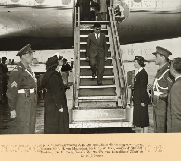 On August 11, HIS Dr. Moh. Hatta arrived and was received by Minister Mr. JH. van Maarseveen, Mr. CLW. Fock, on behalf of the Prime Minister, Dr. H. Boon, on behalf of the Minister of Foreign Affairs, and Dr. MJ. Prinsen, photograph, Arrival of Prime Minister Mohammed Hatta at Schiphol on August 11. Hatta walks down the stairs of the KLM aircraft. Photo in the photo album with 37 photos of the round table conference held between August 23 and November 2 in The Hague in 1949 between representatives of the Netherlands, the Republic of Indonesia, and the Federal Consultative Body. The copy presented to Prime Minister Willem Drees., photographer: Government Information Service, Schiphol, 1949-08-11, paper, gelatin silver print, gelatin silver print on album page, height 170 mm x width 227 mm, height 292 mm x width 400 mm, Person, Mohammad Hatta, Johannes Henricus van Maarseveen, Round Table Conference (1949), Period, 1949-08-23 - 1949-11-02, A man wearing a dark suit, tie, pocket square, g...