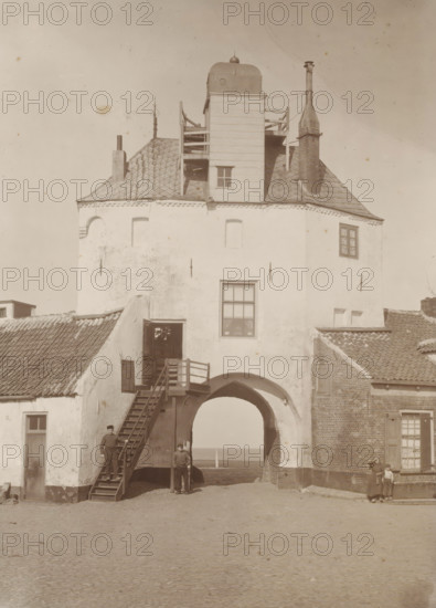 View of the Vischpoort in Harderwijk, photograph, annotation: '1905 Harderwijk, From the Estate of J. Veth, 1972', inscription: 'H. Bickhoff, Amsterdam', photographer: Henri Bickhoff, Harderwijk, 1905, paper, pasteboard, daylight collodion silver print, height 360 mm x width 299 mm, city-gate (city(-scape) with figures, staffage), Vispoort, A tall white plastered building with a tiled roof and chimney features a large arched passage at its base, an external wooden staircase leading to an upper doorway, a square window above the arch, and a wooden tower-like structure rising from the roof with railings and a small window; three men stand near the arch and staircase while a woman and a small child stand near the adjacent brick building, and the ground in front is a cobbled open area.