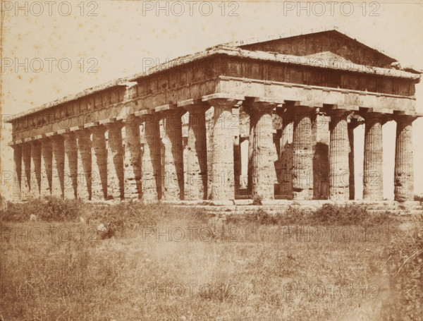 Tempio di Nettuno, Temple of Neptune, Paestum, Italy, Pesto, photograph, number: 'No. 4116 ?', collector's mark: 'VOSMAER', photographer: attributed to Giorgio Sommer, 1857 - 1914, Giorgio Sommer, photographer, Attributed to, pasteboard, paper, albumen print, albumendruk, height 319 mm x width 478 mm, ruin of a building, architecture, temple, shrine, non-Christian religions, Second Temple of Hera, A wide sepia-toned photograph of a large ancient stone temple with a long row of fluted columns supporting an entablature and a pitched roof, the columns showing weathering and irregular surface texture, shadows cast between them, and gaps where inner spaces are visible; the temple sits on a raised platform with a rough foreground of grass and low vegetation extending toward the viewer, and the sky above is pale with scattered small blemishes on the photographic surface.