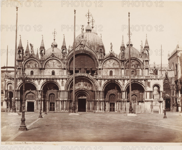 Chiesa S. Marco (Venezia), View of San Marco in Venice, Italy, photograph, number: '43', number: '3592.', collector's mark: 'RICH SCHOOL FOR ART HANDBOOK, GROUP', photographer: attributed to Giorgio Sommer, Venice, 1857 - 1914, Giorgio Sommer, photographer, Attributed to, pasteboard, paper, albumen print, height 319 mm x width 479 mm, church (exterior), Basilica of San Marco, St. Mark's Square, A wide frontal view of a large ornate building façade with multiple domes and spires, richly decorated archways and sculpted figures, mosaic panels set within arched recesses, tall flagpoles and ornate lamp posts standing in the open paved foreground, layered columns and carved reliefs around doorways and windows, and a broad empty square stretching toward the building.