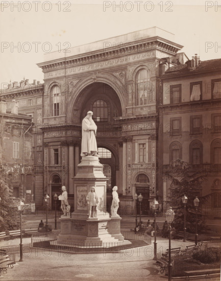 Leonardo da Vinci, Statue of Leonardo da Vinci in Milan, Italy, Milano, photograph, number: '25', number: '1939.', inscription: 'II', photographer: attributed to Giorgio Sommer, Milan, after sculpture by Pietro Magni, 1872 - 1914, Pietro Magni, after sculpture by, Lombardy, Attributed to, pasteboard, paper, albumen print, albumendruk, height 479 mm x width 320 mm, Person, piece of sculpture, reproduction of a piece of sculpture, monument, statue, square, circus, A large ornate stone archway with decorative carvings and tall arched windows dominates the background, flanked by multi-story buildings with shuttered windows and tiled roofs; in front of the arch stands a tall pedestal supporting a robed statue of a standing figure, surrounded at the pedestal corners by additional smaller statues; a paved plaza with low metal fencing, curved benches, vintage street lamps, and a few seated and standing people fills the foreground, while trees and architectural details frame the scene.