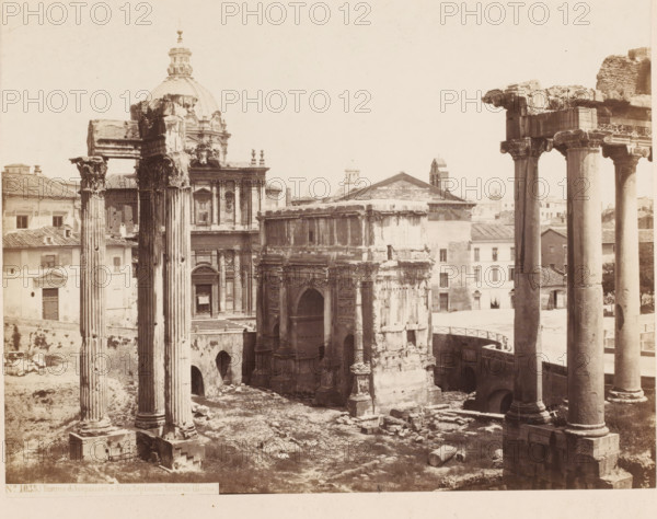 Tempio di Vespasiano e Arco di Septimus Severus (Roma), Ruin of the temple of Vespasian and the triumphal arch of Septimus Severus in Rome, Italy, photograph, inscription: 'Roma', number: '5', number: 'No. 1035.', inscription: 'C. 85.', address: 'SOMMER & BEHLES, ROMA E NAPOLI', photographer: Sommer & Behles, Rome, 1867 - 1874, pasteboard, paper, albumen print, height 322 mm x width 379 mm, ruin of a building, architecture, triumphal arch, gate, entrance, scenes, anonymous historical person(s), Arch of Septimius Severus, Temple of Vespasian and Titus, A sepia-toned photograph showing ancient stone ruins and classical architecture with tall fluted columns topped by ornate capitals standing in the foreground and framing a partially intact arch and a rectangular building with a pediment. A domed church with decorative sculptural details and a facade with pilasters and a doorway is visible behind the ruins, along with rows of tiled-roof buildings. Weathered stone blocks, broken column drum...