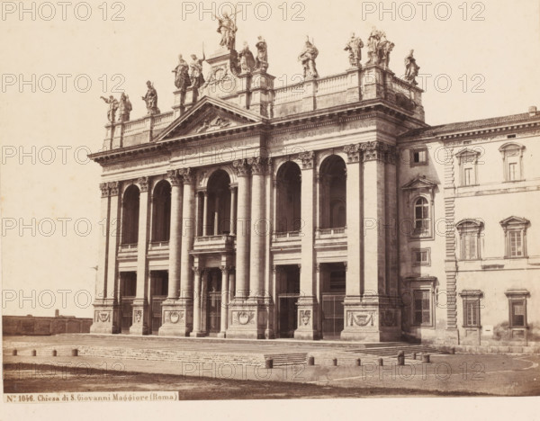 View of the Basilica of St. John Lateran in Rome, Italy, Chiesa di S. Giovanni Maggiore (Roma), photograph, number: '2.', inscription: 'Roma', address: 'SOMMER & BEHLES, ROMA E NAPOLI', number: 'No. 1046.', inscription: 'C. 85.', photographer: Sommer & Behles, Rome, 1867 - 1874, pasteboard, paper, albumen print, height 321 mm x width 382 mm, church (exterior), Sint-Jan van Lateranen, A sepia-toned photograph showing the façade of a large classical building with tall columns and arched openings, a wide flight of steps leading up to the entrance, and decorative relief panels at the column bases; a balustraded upper terrace topped by a row of statues standing on pedestals is visible along the roofline; adjacent to the main façade is a connected wing with rectangular windows and pilasters, and the foreground shows a paved open area with short cylindrical bollards and a textured surface.