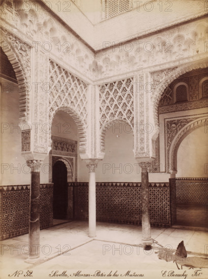 Courtyard of the Alcazar in Seville, No. 52, photograph, Seville, Alcazar - Patio de las Muñecas., photographer: Emilio Beauchy, c. 1867 - c. 1880, pasteboard, paper, albumen print, height 386 cm x width 290 cm, palace, Andalusia, Royal Palace of Seville, A stone courtyard corner with ornate carved arches and patterned wall tiles, showing slender columns with decorative capitals supporting horseshoe-shaped arches, intricately carved plaster latticework and geometric reliefs above and between the arches, a tiled dado with repeating star and polygon patterns, a smooth paved floor with recessed channels, a dark recessed doorway beneath one arch, and a large fallen leaf lying on the floor near one column.