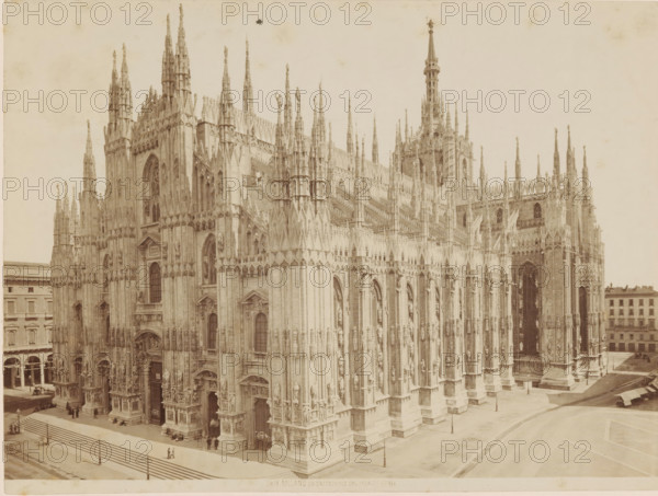 Milan Cathedral, MILAN. LA CATTEDRALE DAL PALAZZO REALE, photograph, number: '3818.', Milan, c. 1875 - c. 1900, photographer, Lombardy, paper, pasteboard, albumen print, height 185 mm x width 248 mm, church (exterior), Dom (Milan), A large Gothic cathedral façade fills the frame with numerous tall pointed spires and pinnacles rising from ornate buttresses and decorative vertical elements; the stone exterior shows many carved statues set into niches, arched doorways with sculpted surrounds, and traceried windows with pointed arches. The foreground shows a paved plaza with steps leading up to the building, a low railing, and a few small groups of people standing or sitting near the entrances. To the right, the cathedral continues with more flying buttresses and a tall central tower topped by a slender spire. Along the left and right edges of the image, multi-story buildings with rows of windows and arcades are visible, and a few street lamps and horse-drawn carriages can be seen near the...