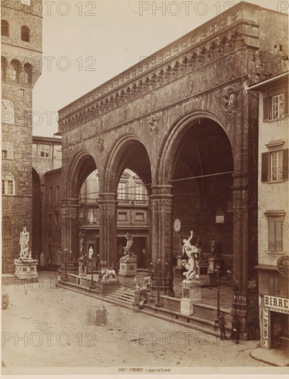 FIRENZE. Loggia de'Lanzi, Loggia dei Lanzi in Florence, photograph, number: '3057.', annotation, Florence, c. 1875 - c. 1900, photographer, Tuscany, paper, pasteboard, albumen print, albumendruk, height 260 mm x width 199 mm, piece of sculpture, reproduction of a piece of sculpture, loggia, verandah, porch, Toscane, Loggia dei Lanzi, A sepia photograph of a stone loggia with three large rounded arches supported by ornate columns, decorative reliefs along the upper façade, and sculpted figures attached to the exterior; beneath the arches are shadows and architectural details including a clock on the wall and additional statues and pedestals; in front of the loggia on a paved square are multiple freestanding marble sculptures on plinths, lampposts, low balustrades, and steps leading up to the raised platform; to the left a tall stone tower with arched windows and a standing statue at its base is visible, while to the right a building with shuttered windows frames the scene; a few blurred...