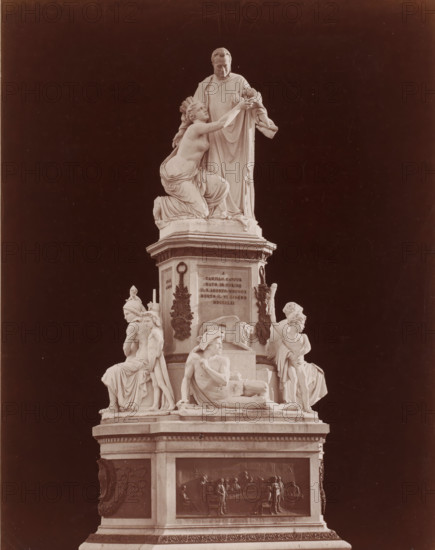 Monument to Camillo Cavour on the Piazza Carlo Emanuele II in Turin, Italy, Piazza Carlo Emanuele II. - Monumento a Camillo Cavour, Giovanni Dupré, Torino, photograph, number: '3673. bis', photographer: attributed to Giacomo Brogi, Turin, publisher: attributed to Edizioni Brogi, Florence, after sculpture by Giovanni Dupré, 1873 - 1881, after sculpture by, Tuscany, Piedmont, Attributed to, pasteboard, paper, albumen print, height 445 mm x width 318 mm, Person, Camillo Benzo Duke of Cavour, piece of sculpture, reproduction of a piece of sculpture, historical persons, monument, statue, Piemonte, Piazza Carlo Emanuele Secondo, A multi-tiered marble monument set against a dark background with a central standing male figure draped in robes looking downward while a partially draped female figure kneels beside him reaching upward toward his hands; below them a pedestal adorned with sculpted reliefs and decorative wreath elements, flanked by seated and reclining figures in classical drapery inc...