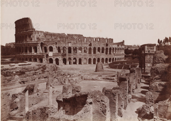 View of the Colosseum in Rome, Italy, Colosseo, Roma, photograph, number: '4222.', number: '104.', photographer: Giacomo Brogi (possibly), Rome, publisher: attributed to Edizioni Brogi, Florence, 1864 - 1881, Tuscany, Attributed to, pasteboard, paper, albumen print, albumendruk, height 317 mm x width 445 mm, ruin of a building, architecture, landscape with ruins, amphitheatre, Colosseum, A wide sepia photograph shows an ancient stone amphitheater with multiple tiers of arched openings and a partially ruined outer wall, foregrounded by excavated ruins of brick and stone foundations and scattered columns. The amphitheater curves across the scene with a rounded, taller section on the left and a lower, arcaded stretch toward the right. In front of the amphitheater there is an open dirt area with a circular raised stone feature and a freestanding cylindrical structure. To the right of the amphitheater stands a decorated stone arch with relief panels, flanked by more rubble and vegetation. T...