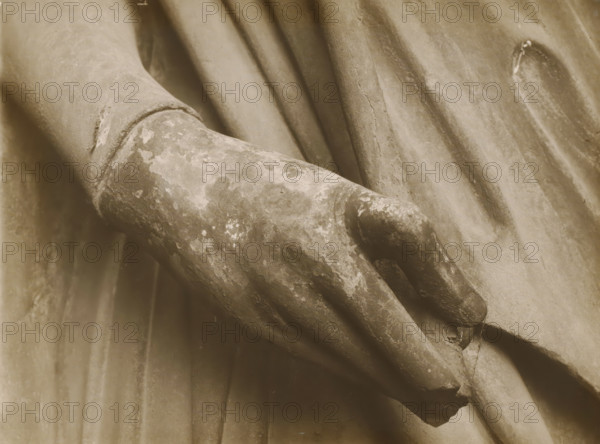 Adamspforte (r.Hand), Detail of the Adamspforte in Bamberg Cathedral, album page, photograph, This photo is part of an album., number: '47.', Bamberg, 1900 - c. 1920, photographer, Bavaria, paper, baryta paper, gelatin silver print, developed gelatin silver print, height 227 mm x width 168 mm, church (exterior), Bamberg Cathedral, A close-up sepia-toned view of a weathered stone hand resting against draped fabric, showing textured surface wear and flaking, with visible folds and creases in the surrounding cloth.