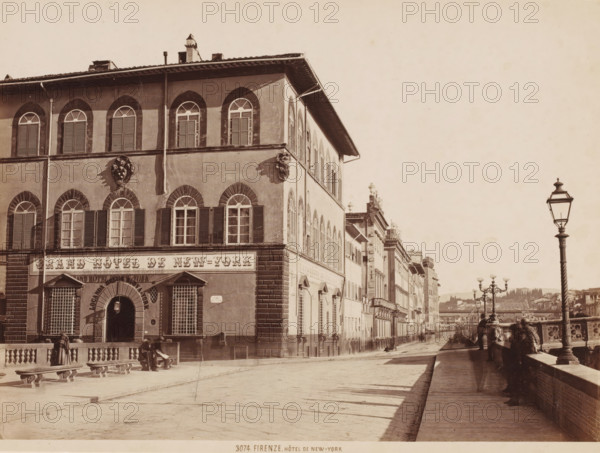 Grand Hotel de New-York, Florence, Italy, photograph, View in a street along the Arno?, with the Grand Hotel de New-York on the left, and the boulevard on the right., caption: '3074. FIRENZE. HôTEL DE NEW-YORK', inscription: 'Brogi 1870's', check stamp: 'GIACOMO BROGI, PHOTOGRAPHER-EDITORE, FIRENZE, LUNG ? ARNO DELLE GRAZIE 15', photographer: Giacomo Brogi, publisher: Giacomo Brogi, c. 1860 - c. 1890, Giacomo Brogi, photographer, publisher, Tuscany, pasteboard, paper, albumen print, height 190 mm x width 253 mm, height 349 mm x width 470 mm, A sepia-toned street scene showing the corner of a multi-story building with shuttered arched windows and decorative stone faces on its facade, a large arched doorway with metal grilles over lower windows, stone balustrades and benches along the sidewalk, a row of adjacent buildings stretching down the street with repeating arched windows and shutters, ornate street lamps along a riverside promenade, people standing and walking near the balustrade,...