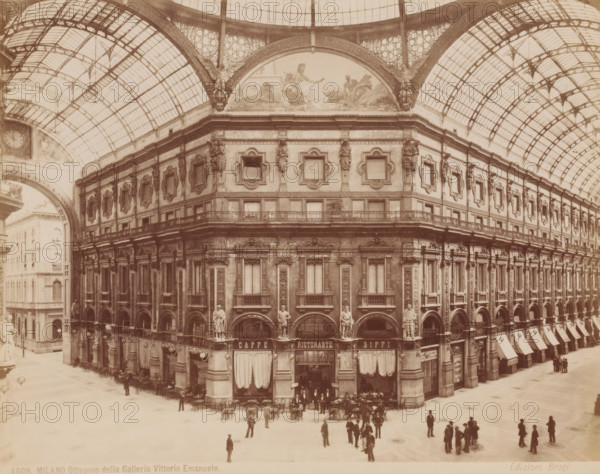 Dome of Galleria Vittorio Emanuele, Milan, Italy, photograph, Italy., caption: '4608. MILANO. Ottagono della Galleria Vittorio Emanuele', caption: '(EDIZIONI BROGI)', photographer: Edizioni Brogi, Florence, publisher: Giacomo Brogi, c. 1860 - c. 1890, Tuscany, pasteboard, paper, albumen print, height 197 mm x width 249 mm, height 492 mm x width 330 mm, Lombardy, Galleria Vittorio Emanuele, A sepia photograph showing an ornate multi story building under a large glass and iron vaulted roof, the facade decorated with sculpted figures set in niches, framed window surrounds with ornamental cartouches, and a balcony running along the upper level; beneath the arches at street level are shopfronts with canopies and curtains, tables and chairs arranged outside, and small groups of people standing and walking in the open plaza in front; overhead the arched glass ceiling features a lattice of metal ribs and patterned panes, and the curved pediment above the building displays a painted scene flank...