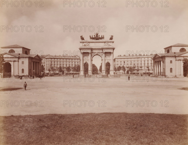 Veduta d'assieme con Arco della Pace, Milan, Italy, photograph, Italy., caption: '12291. MILANO - Veduta d'assieme con l 'Arco della Pace.', caption: '(EDIZIONI BROGI)', photographer: Edizioni Brogi, Florence, publisher: Giacomo Brogi, c. 1860 - c. 1890, Edizioni Brogi, Giacomo Brogi, photographer, publisher, Tuscany, pasteboard, paper, albumen print, height 250 mm, width 200 mm x width 510 mm, height 330 mm, Lombardy, A wide open plaza with a central monumental arch topped by a sculptural group of horses and figures, flanked on either side by classical buildings with columns and arched openings, a line of multi-story buildings behind the arch, trees and fencing near the buildings, a few people and horse-drawn carts near the side buildings and a couple of solitary figures in the open area, and a foreground of grass leading to the bare expanse of the plaza.