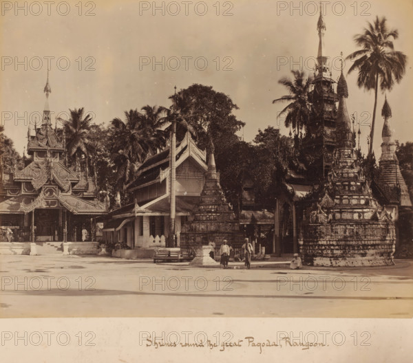 Shrine around the Shwedagon Pagoda, Yangon, Myanmar, album page, photograph, Pagoda with burial chambers and palm trees, taken from an open area. The country has officially been called the Union of Myanmar since 1989; before that, it was called Burma. Since November 7, 2005, the capital has officially been the centrally located Naypyidaw (near Pyinmana), although the relocation only began on that date. The former capital is Rangoon (Yangon), the largest city in the country., caption: 'Shrines round the great Pagoda, Rangoon', c. 1880 - c. 1900, photographer, paper, pasteboard, albumen print, height 206 mm, width 268 mm x width 301 mm, height 380 mm, A wide sepia photograph showing ornate temple buildings and stupas with tiered, carved roofs and spires, surrounded by tall palm trees and dense foliage, with a large open paved area in the foreground and a few people standing and sitting near the base of one of the stupas.