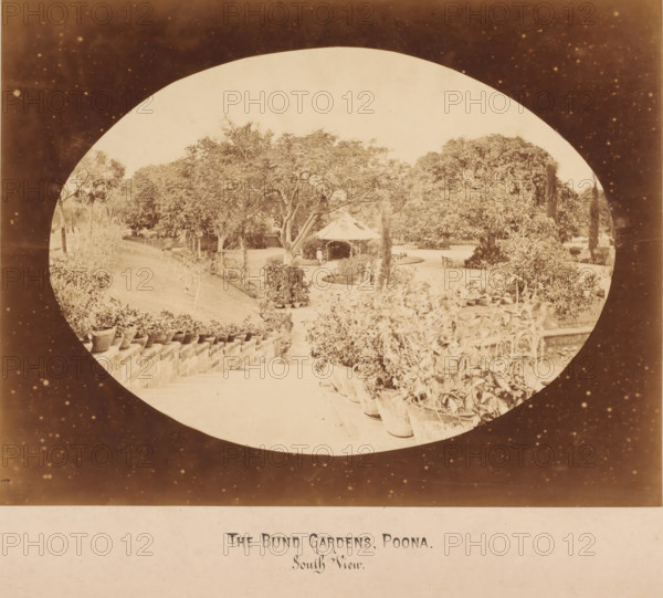 The Fitzgerald bridge, Bund Gardens and River, Poona, India, photograph, Oval photo of a bridge with a river and a park on the left. Poona, also called Pune and Puna and formerly Punavadi, is an Indian city not far from Bombay in the Western Ghats. The city is located in the district of Pune with the same name., inscription: 'THE BUND GARDENS, POONA., South View.', inscription: 'The Bund Gardens - Poona, South View', photographer: attributed to X photot., c. 1875 - c. 1900, X photo., Attributed to, A sepia-toned photograph framed by a circular vignette shows a garden scene with a paved walkway flanked by rows of potted plants and low stone or brick steps, trees with spreading branches and dense foliage filling the middle ground, a small pavilion with a conical roof partially obscured by trees, a person standing near the pavilion, benches positioned near curved pathways, and various shrubs and planters arranged along the paths and terraces.