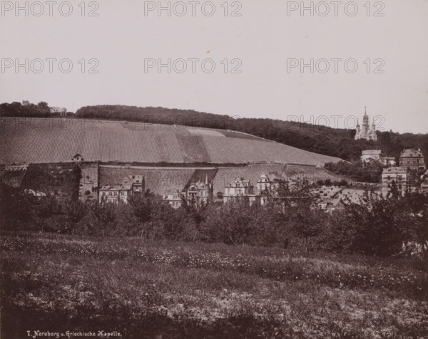 Greek Chapel', Russian Orthodox Church on Mount Nero, Wiesbaden, Germany, photograph, Erroneously named 'Greek Chapel' Russian Orthodox church 'of Saint Elisabeth in Wiesbaden', which Adolf von Nassau had built between 1847-1855 as a tomb for his young deceased wife Elisabeta Mikhailovna (daughter of the younger brother of Tsars Alexander I and Nicholas I of Russia)., inscription: '7. Neroberg u. Griechische Kapelle.', c. 1890 - c. 1900, photographer, pasteboard, paper, collotype, photogravure, height 282 mm, width 225 mm x width 330 mm, height 508 mm, Hessen, A wide panoramic view showing a sloping hillside covered in rows of cultivated vines with a dense tree line at the ridge, a cluster of ornate multi-story houses with steep roofs and decorative facades at the foot of the hill, a domed chapel and a larger church with multiple domes and spires rising above the trees on the right, scattered trees and grassy foreground with wildflowers, and a few small structures and terraced walls in...