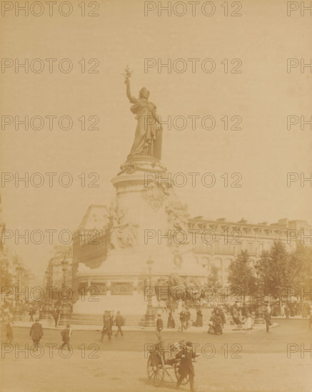 Place de la République, Paris, France, photograph, France., check stamp: 'Photography Company, J. KUHN, 220 170 174 Rue de Rivoli', inscription: '128 Paris. Place de la Republique', publisher: J. Kühn (publisher), c. 1885 - c. 1910, paper, albumen print, height 276 mm, width 218 mm x width 342 mm, height 402 mm, A large stone monument topped by a standing female statue holding a branch dominates the center, with sculpted reliefs and seated figures around its cylindrical base; surrounding the monument are multi-story buildings with rows of windows and mansard roofs, streetlamps, trees, and a crowd of people dressed in period clothing walking and gathering around the plaza, while in the foreground a man pulls a two-wheeled cart across the open paved square.