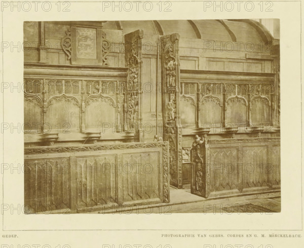 Choir stalls in the Martinikerk in Bolsward, photograph, inscription: 'Gedep., Photographie van gebrs. Cordes en GM Märckelbach', inscription: 'De Bolswardsche koorbanken, Ned. Kunstbode I, 1879 p.263', photographer: Cordes, Gebroeders, Bolsward, 1879, paper, pasteboard, albumen print, albumendruk, height 158 mm x width 229 mm, height 215 mm x width 280 mm, parts of church exterior and annexes: chapel, Martinikerk (Bolsward), The image shows a section of intricately carved wooden choir stalls with ornate panels and decorative arches along the upper portion, including carved vertical end pieces with figurative and floral reliefs; a narrow aisle between stalls is visible with a carved stall door partially open, revealing more carved details on its inner face; the wood has a worn, aged appearance with visible grain and patina, and a curved wooden ceiling element is visible above the stalls.