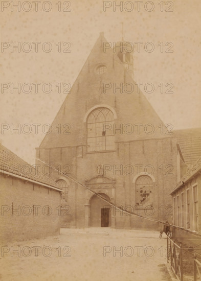 Westerkerk in Harlingen, shortly before its demolition in 1896, photograph, annotation: 'Harlingen', annotation: 'Westerkerk in Harlingen (Fr), July 1896', Harlingen, photographer: AJM Mulder (possibly), 1896, Attributed to, paper, pasteboard, albumen print, height 228 mm x width 165 mm, church (exterior), A large brick building with a steep triangular roof dominates the scene, featuring a tall arched window near the center and smaller arched windows lower on either side, some of which have broken panes; a decorative stone entrance with a carved crest sits beneath the central window and an open doorway leads into a dark interior; to the left and right, lower brick structures with tiled roofs flank a wide open courtyard that extends toward the foreground, where the ground appears bare and slightly uneven; a narrow railing runs along the right side of the courtyard and a slanted pole or beam crosses diagonally from the right toward the lower left; near the top of the main roof a small be...