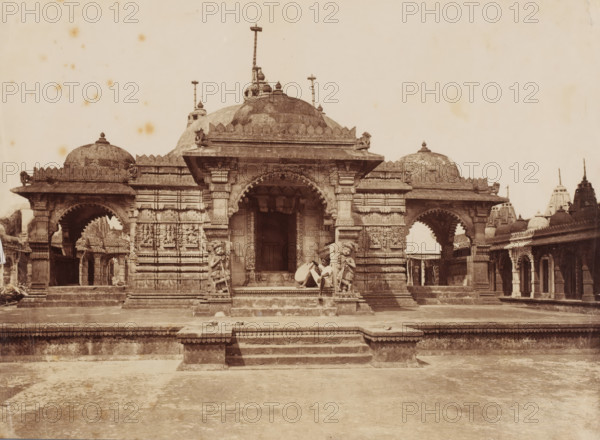 Temple complex, Palitana, Gujarat, India, photograph, Palitána ?, India., inscription: 'Palitana', c. 1870 - c. 1900, photographer, paper, albumen print, height 239 mm x width 177 mm, A wide stone temple facade with domed roofs and carved pillars sits centered on a raised platform accessed by a short flight of steps, flanked by arched porticoes on either side and smaller domed structures in the background; ornate sculptural reliefs decorate the walls and pillars, and two carved guardian figures stand beside the central entrance where a seated person rests against one pillar holding an object; the foreground shows a broad paved courtyard leading to the temple and scattered small objects on the steps and platform.