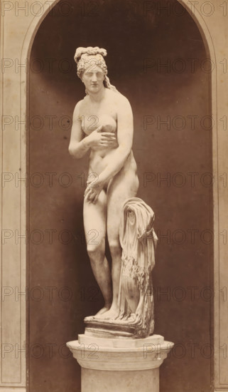 Capitoline Venus, photograph, photographer: Libreria Spithöver, c. 1850 - c. 1870, pasteboard, paper, albumen print, albumendruk, height 350 mm x width 212 mm, piece of sculpture, reproduction of a piece of sculpture, Rome, Capitol, A pale marble statue of a nude female figure stands on a round pedestal within a tall arched niche, the figure shown in a contrapposto pose with one arm crossing her chest and the other resting near her thigh, her hair styled and tied up with a draped cloth hanging beside her, the background and niche interior are darker and smooth, and the overall image has a warm sepia tone.