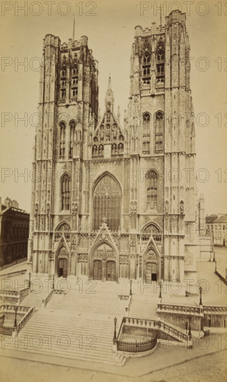 Bruxelles. Façade de Ste-Gudule, Cathedral of Saint Michael and Saint Gudula in Brussels, photograph, page, Brussels, c. 1875 - c. 1880, photographer, paper, albumen print, albumendruk, height 172 mm x width 102 mm, church (exterior), facade (of house or building), Cathedral of Saint Michael and Saint Gudula, A sepia-toned photograph of a large Gothic cathedral façade with two tall towers flanking a central pointed arch window and ornate sculpted gables, detailed tracery and vertical buttresses. The lower section shows three large pointed doorways with carved tympana and decorative niches above, multiple narrow lancet windows higher up, and rows of sculpted figures in recessed panels. Broad stone steps lead up to the entrance, bordered by balustrades and lamp posts, with smaller staircases and fenced curved landings at the sides. Adjacent buildings and a street are visible at the edges of the image.