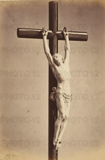 Ivory crucifix from the episcopal chapel in Ghent, displayed at an exhibition of religious objects from the Middle Ages and Renaissance in 1864 in Mechelen, photograph, page, number: '8', photographer: Joseph Maes, Mechelen, 1864, paper, albumen print, height 277 mm x width 197 mm, altarcross, crucifix, piece of sculpture, reproduction of a piece of sculpture (bone, ivory, arts), Period, A sepia-toned photograph of a carved figure of a man affixed to a tall wooden cross, his arms extended upward and hands gripping the horizontal beam, his head tilted to one side with closed eyes, a cloth draped around his waist, detailed musculature and ribs visible on his torso, legs crossed at the ankles and feet overlapping where they are bound, the vertical post of the cross running from top to bottom behind him, the horizontal beam rounded and polished, and a plain neutral background with small specks and age marks.