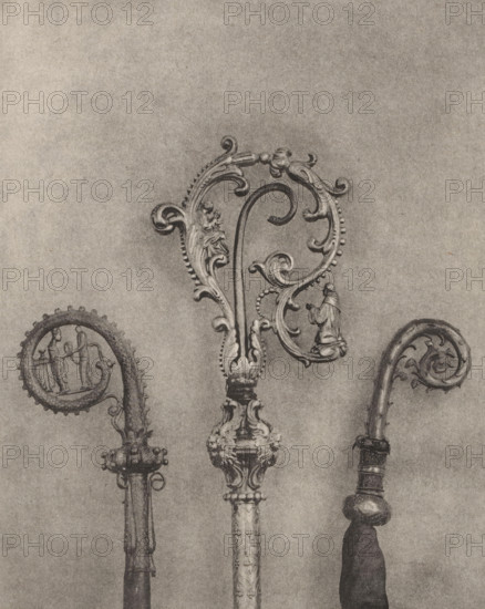 Three decorated episcopal staffs, displayed at an exhibition of religious objects from the Middle Ages and Renaissance in 1864 in Mechelen, page, photomechanical print, number: '-42', number: '1. 2. 3', number: '3 - 1 - 2', photographer: Joseph Maes, Mechelen, clichémaker: Simonau & Toovey, Antwerp, 1864 - in or before 1866, paper, photolithography, height 224 mm x width 180 mm, (liturgical) equipment of church, Period, 1864, Three ornate crook-shaped objects with decorative scrolls are shown against a plain background, each featuring carved embellishments and curved tops. The central piece is the largest with an elaborate swirling design, bead-like edging, floral motifs, and a small figurine integrated into the scrollwork; its shaft has carved ornamentation and a detailed base. The left piece has a rounded curled top with a framed scene incorporated into the curl and a shaft with a rounded, studded collar. The right piece has a narrower curled top with foliate carving, a banded shaft,...