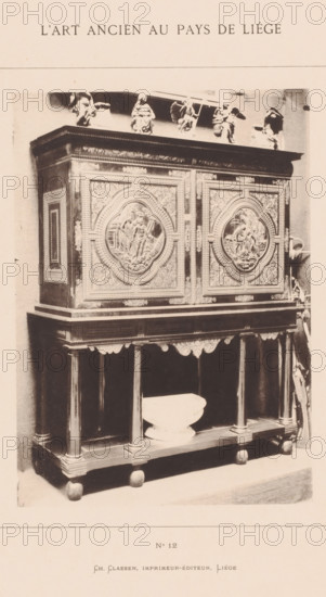 Wooden cabinet, installed in the archaeological museum in Liège, Belgium, L'Art Ancien au Pays de Liége, photomechanical print, This print is part of a cover with twenty prints, a title page and a list of images., number: 'No 12', Liège, printer (person): Ch. Claesen Éditeur, publisher: Ch. Claesen Editeur, c. 1879 - in or before 1884, Ch. Claesen Éditeur, printer (person), publisher, paper, collotype, photoprint, height 228 mm x width 162 mm, permanent exhibition, museum, ornamental cupboard (wood and other phytogenic material), A tall ornate wooden cabinet stands on a lower open shelf supported by turned columns and rounded feet, the cabinet doors decorated with large circular relief panels surrounded by intricate carved floral and geometric patterns, a wide cornice with decorative molding tops the piece, small sculpted figures and statuettes are arranged along the top edge, a shallow bowl rests on the lower shelf between the columns, the photograph shows the furniture against a plai...