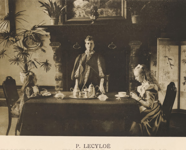 Woman stands behind a table where two children are drinking tea, Sentiment d'Art en Photographie, photomechanical print, This print is part of 8 covers with 22 text sheets and 89 prints on loose sheets in and between the covers., number: 'Vol. 1, No 6, Planche 3.', photographer: P. Lecyloë, clichémaker: anonymous, printer (person): Liorel & Cie., c. 1894 - in or before 1899-03, P. Lecyloë, Liorel & Cie., photographer, clichémaker, printer (person), paper, collotype, photogravure, height 156 mm x width 217 mm, mother and child(ren), woman and child(ren) (family group), cup of tea, A sepia-toned interior scene showing a long table covered with a dark cloth and set with a tea service including a tray, teapot, sugar bowl, cups, and small dishes, flanked by three figures; a woman stands behind the table facing forward with hands resting on the surface, wearing a patterned dress and a shawl, and two girls sit at opposite ends of the table facing inward, each with long hair and dressed in per...