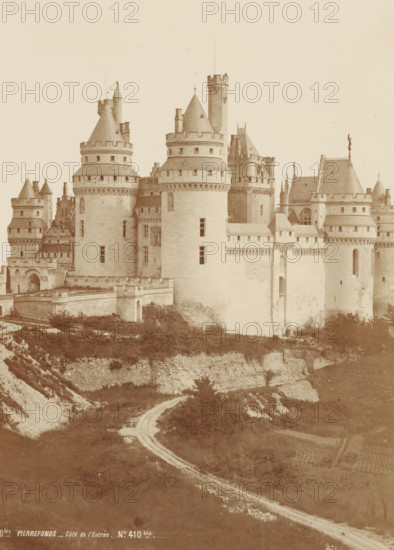 Vue d'Ensemble - Côté de l'entrée, View of the castle of Pierrefonds, France, Chateau de Pierrefonds, photograph, page, number: 'PL. 1', inscription: 'No. 410bis PIERRE FUND. - Côté de l'Entrée. No. 410bis.', photographer: Séraphin-Médéric Mieusement, Pierrefonds, publisher: Ducher & Cie., c. 1870 - in or before 1875, Séraphin-Médéric Mieusement, Ducher & Cie., photographer, publisher, paper, albumen print, albumendruk, height 351 mm x width 250 mm, castle, Pierrefonds Castle, A large stone castle with multiple rounded towers and conical roofs rises on a cliff, showing crenelated battlements and narrow vertical windows; ornate rooflines and sculptural details appear on some towers, and connecting walls feature small rectangular openings and decorative stonework; a winding dirt path leads up the slope toward the castle, bordered by grassy and rocky terrain with patches of low vegetation; the foreground shows layered earth and stone forming the cliff face beneath the castle.
